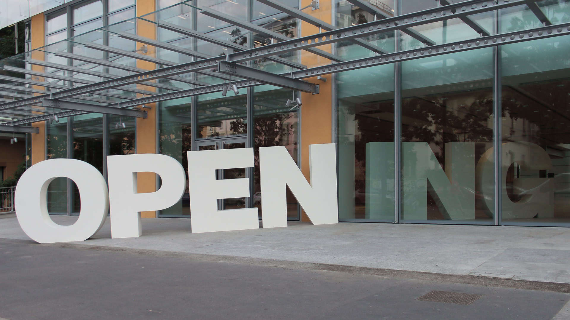 Grandi lettere bianche che compongono la scritta "OPENING" si ergono orgogliose all'esterno di un edificio in vetro all'avanguardia, decorato con un'elegante tenda da sole in metallo. In Modoprint, creiamo prime impressioni d'impatto che parlano da sole. Scopri con noi il potere della precisione e dell'eleganza nella stampa digitale.